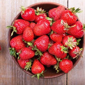 Fresh strawberry in a clay plate  on wooden table , top view